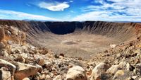 a deep circular crater in a rocky desert landscape