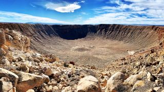 a deep circular crater in a rocky desert landscape