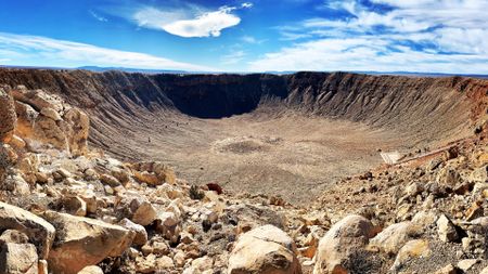 a deep circular crater in a rocky desert landscape