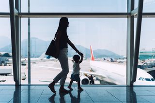 Mother and child walking through airport holding hands