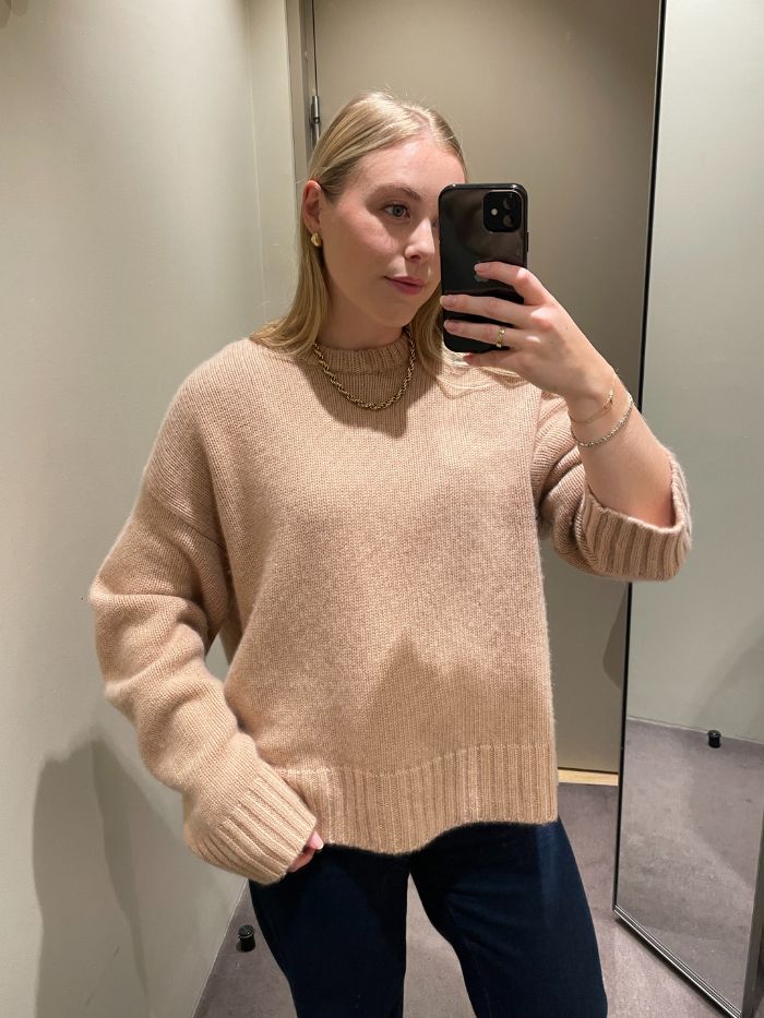 Woman wears beige jumper and blue jeans