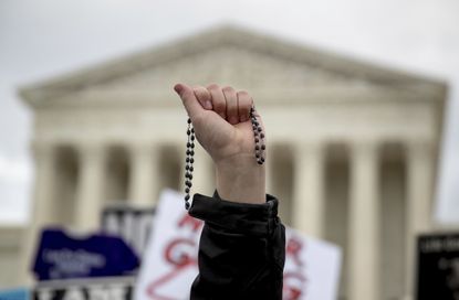 An anti-abortion activist holds up rosary beads in front of the Supreme Court.