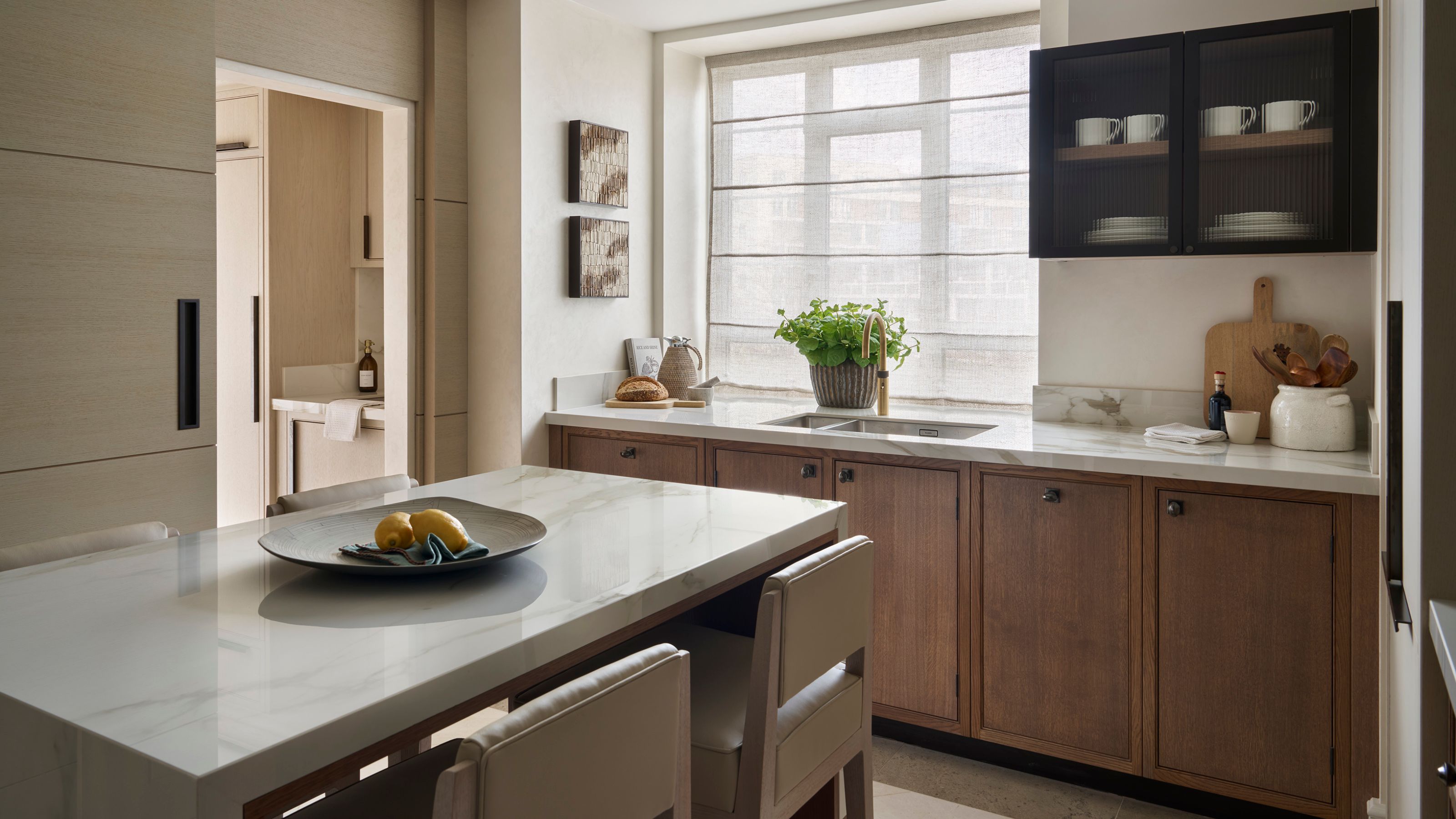 a neutral kitchen with wooden flat panel cabinetry and a small island with bar stools