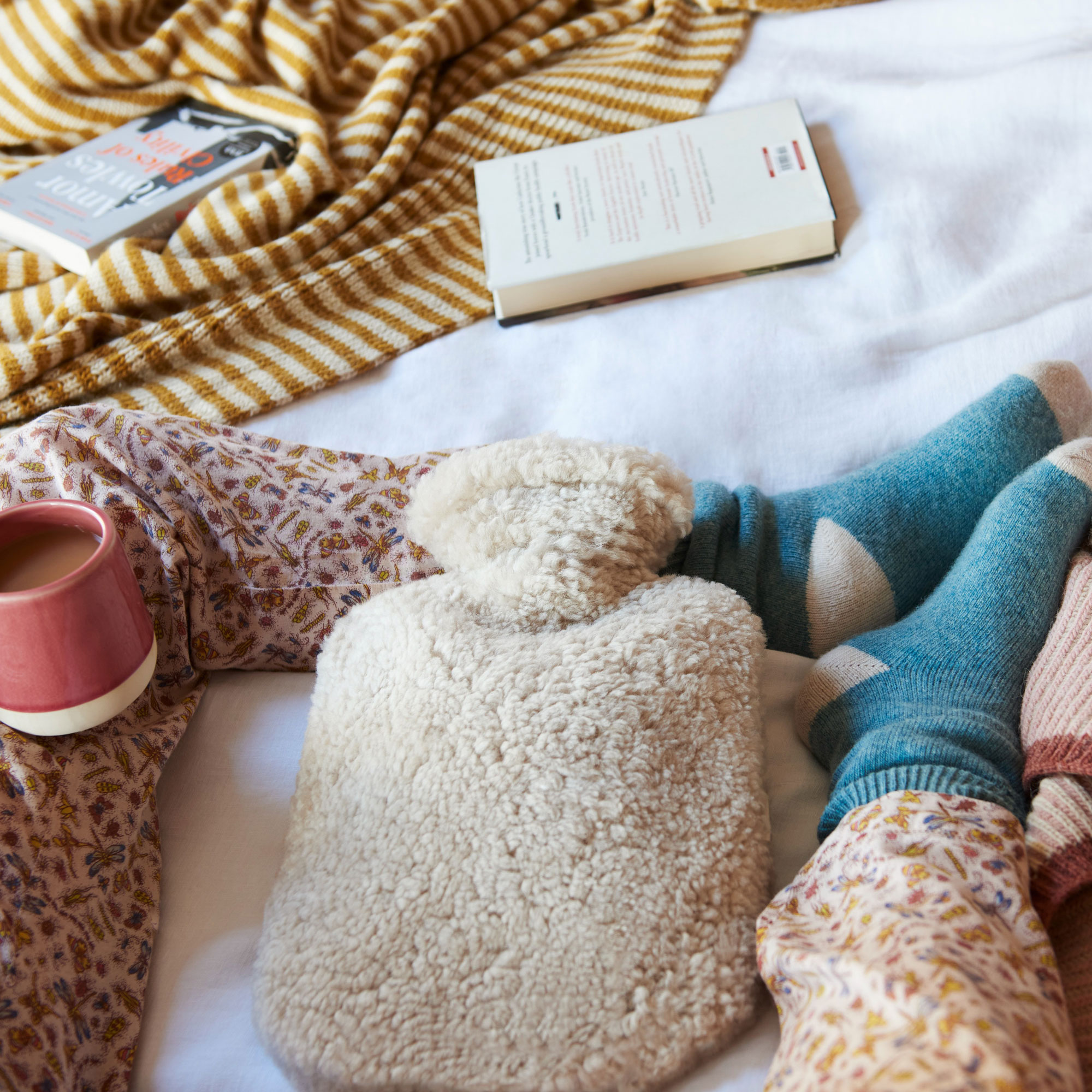 fluffy hot water bottle on bed with mug