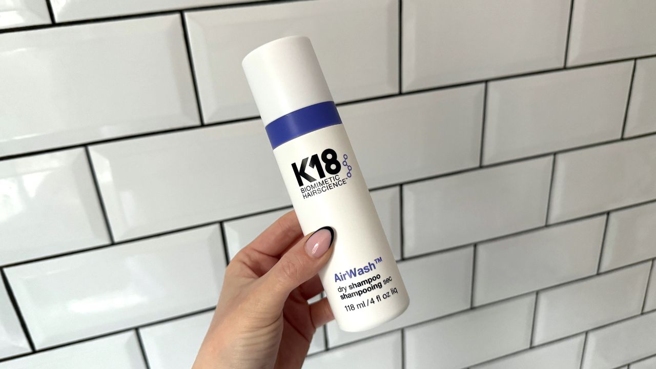 Image of a handheld view of the K18 AirWash Dry Shampoo against a white tiled background 