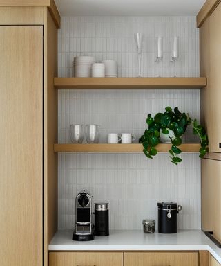 Open wooden kitchen shelving with tile wall and simple white color scheme with houseplants