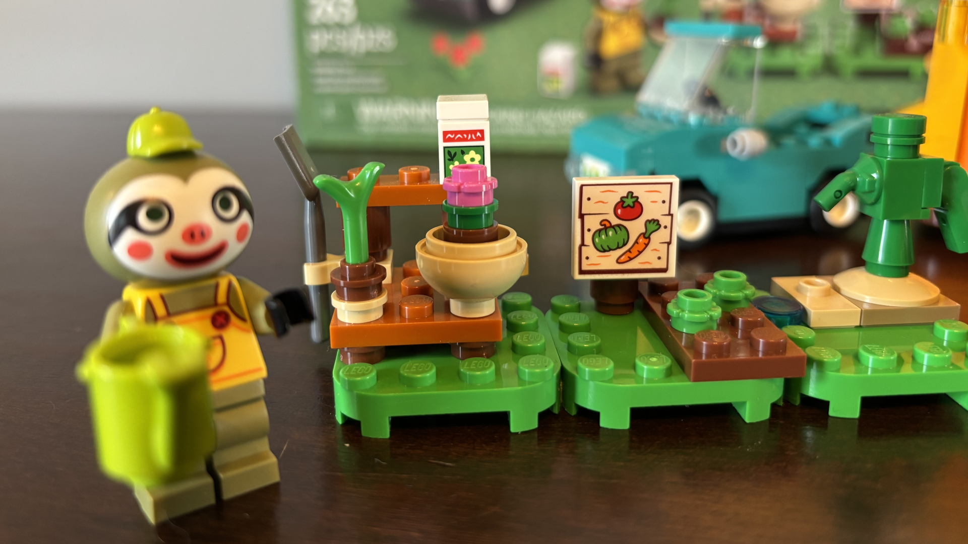 Lego Leif&#039;s Caravan &amp;amp; Garden Shop Leif minifigure alongside a garden shop, all on a wooden surface