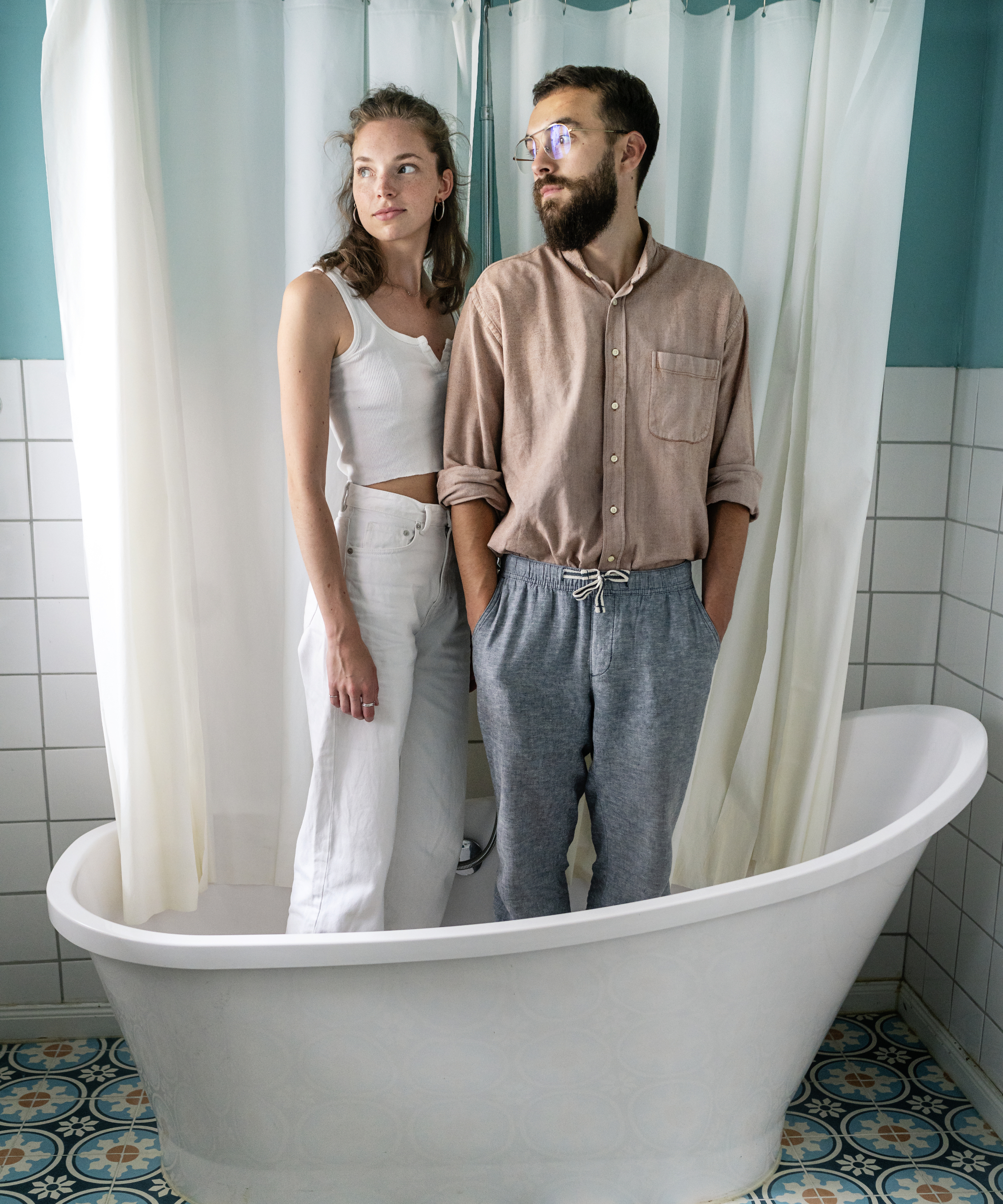 male and female stood in freestanding bath with shower curtain behind them