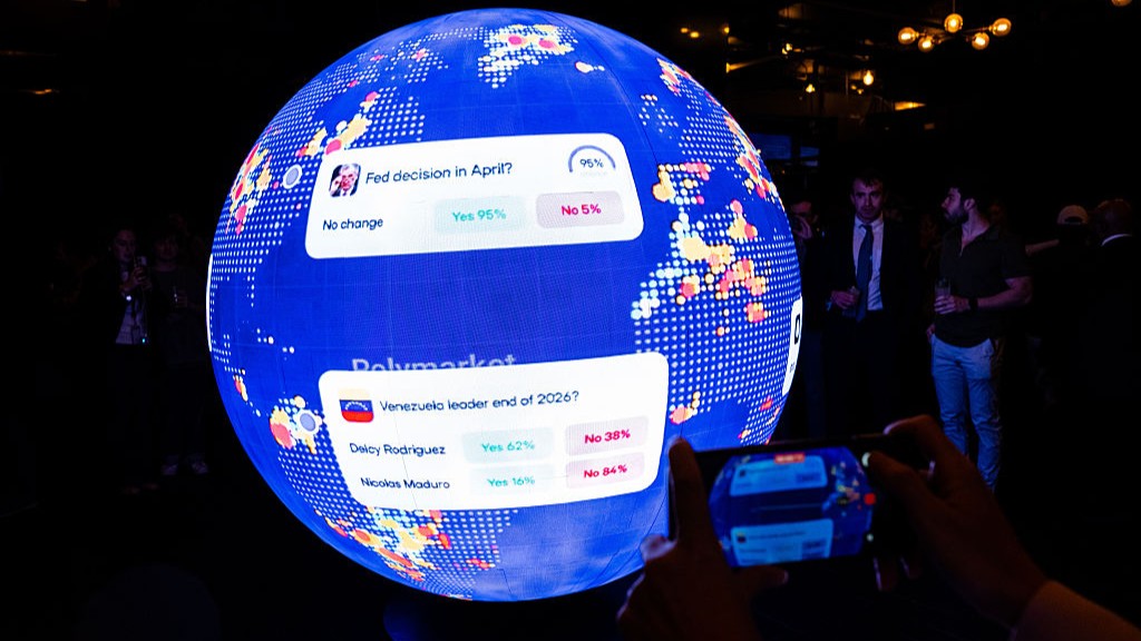 People take pictures of a sphere with prediction market questions on it at a Polymarket event.