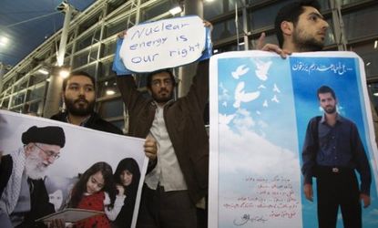 Iranian students carry pictures of the nuclear scientist who was killed in a bomb blast this month as they wait for the arrival of U.N. nuclear experts.