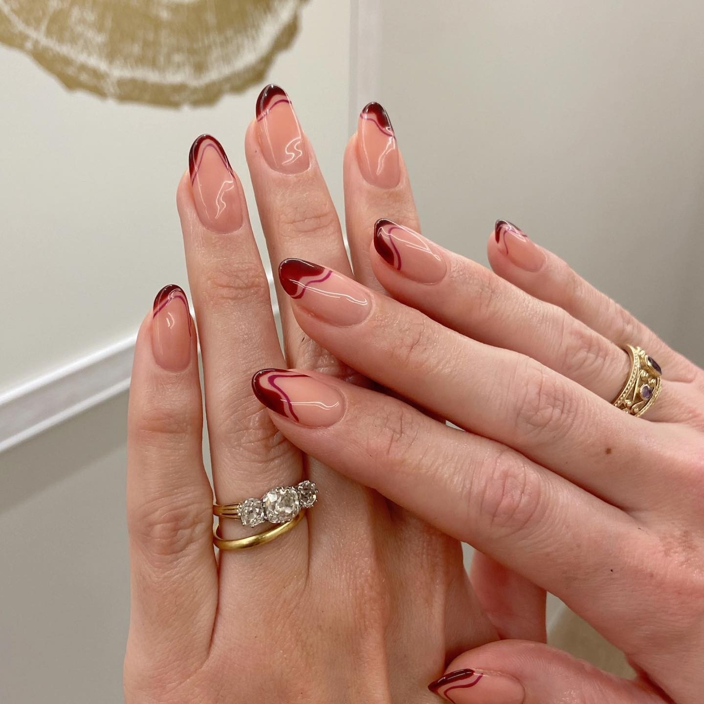 A clear manicure with red swirl French tips