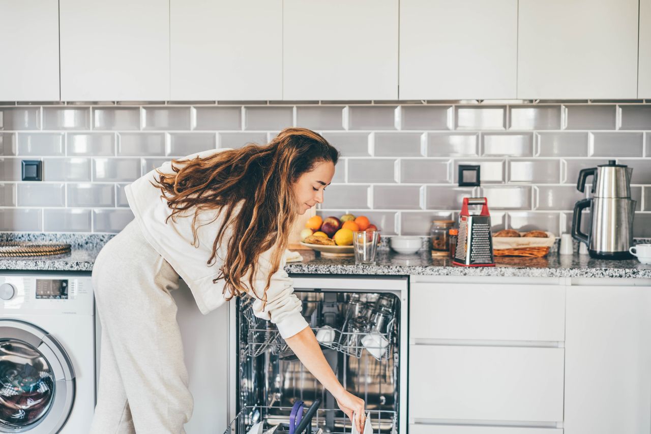 A woman loading an open dishwasher.