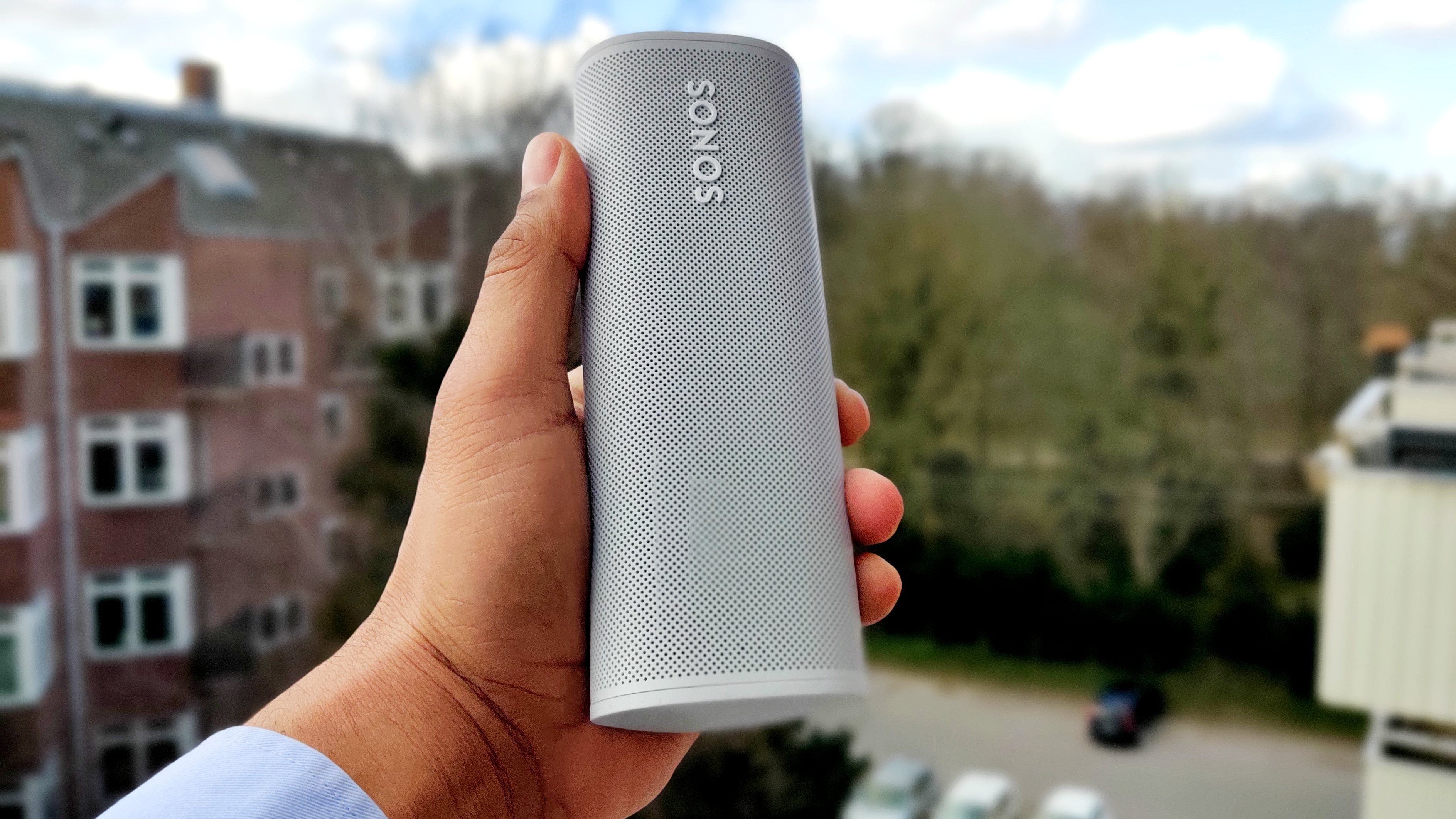Sonos Roam held in a hand outdoors