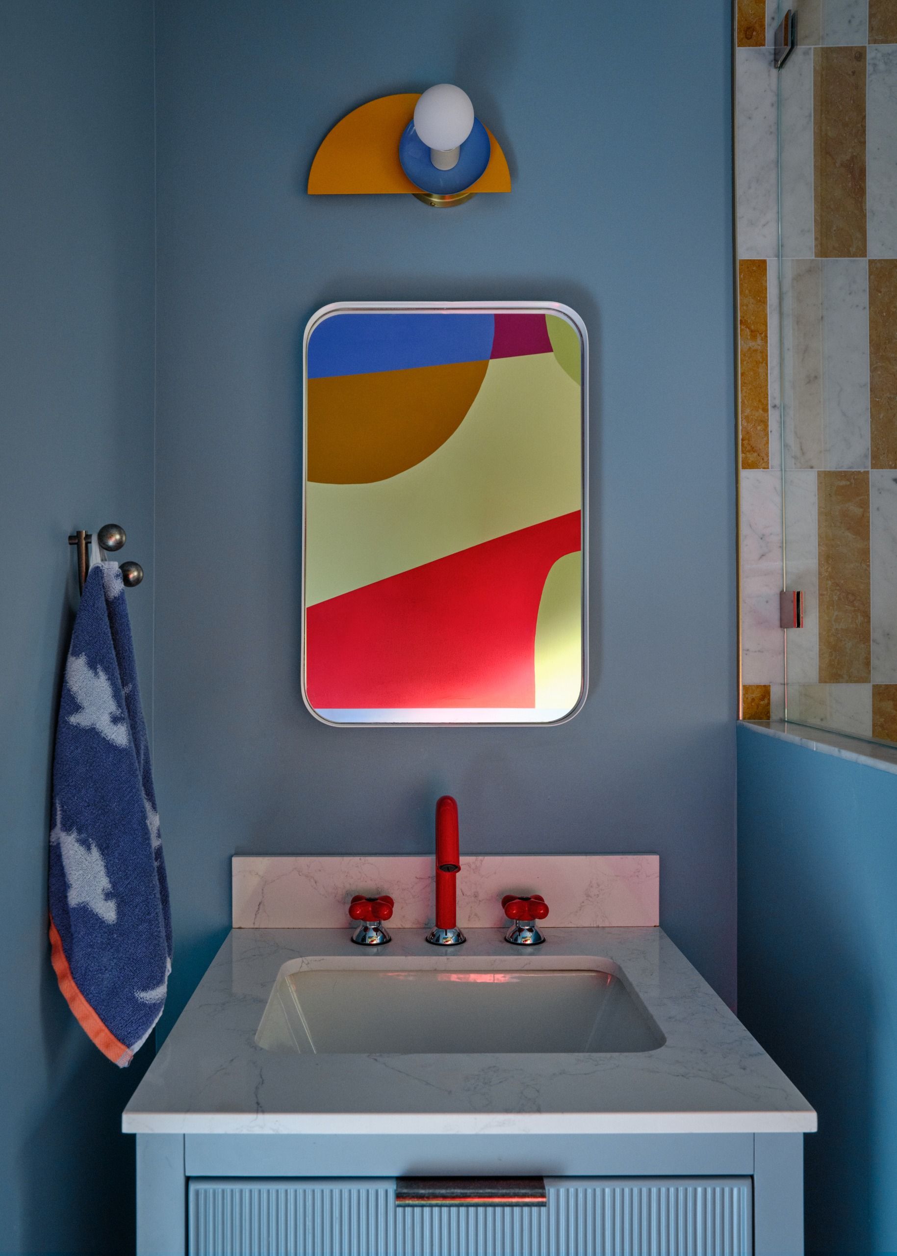 A bathroom with blue walls, a marble vanity and fluted storage 
