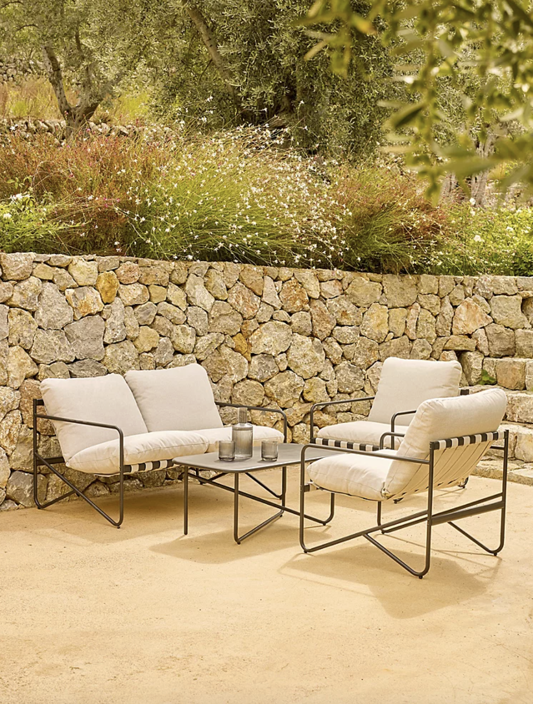 George Home, Tuscany 4 Piece Garden Sofa Set Black in garden with stone wall behind