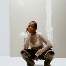 Keke Palmer wearing black pants and a white sheer top over a white bralette