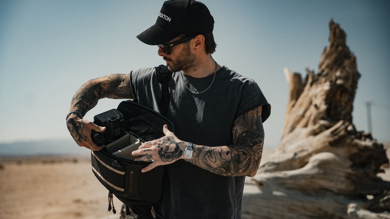 A photographer grabs gear out of the PolarPro RoadRunner Shoulder Bag