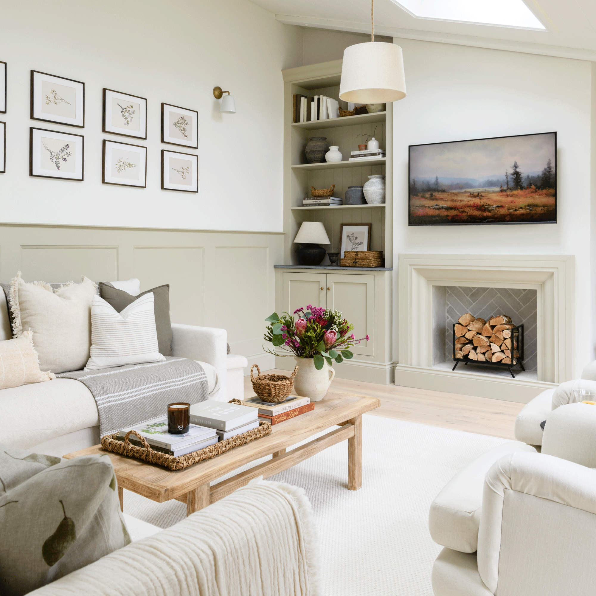 a living area in an open plan space with a fireplace, alcove shelving and white sofa and armchairs