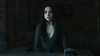 Ana de Armas' Eve sitting at table with a disassembled gun on it in Ballerina