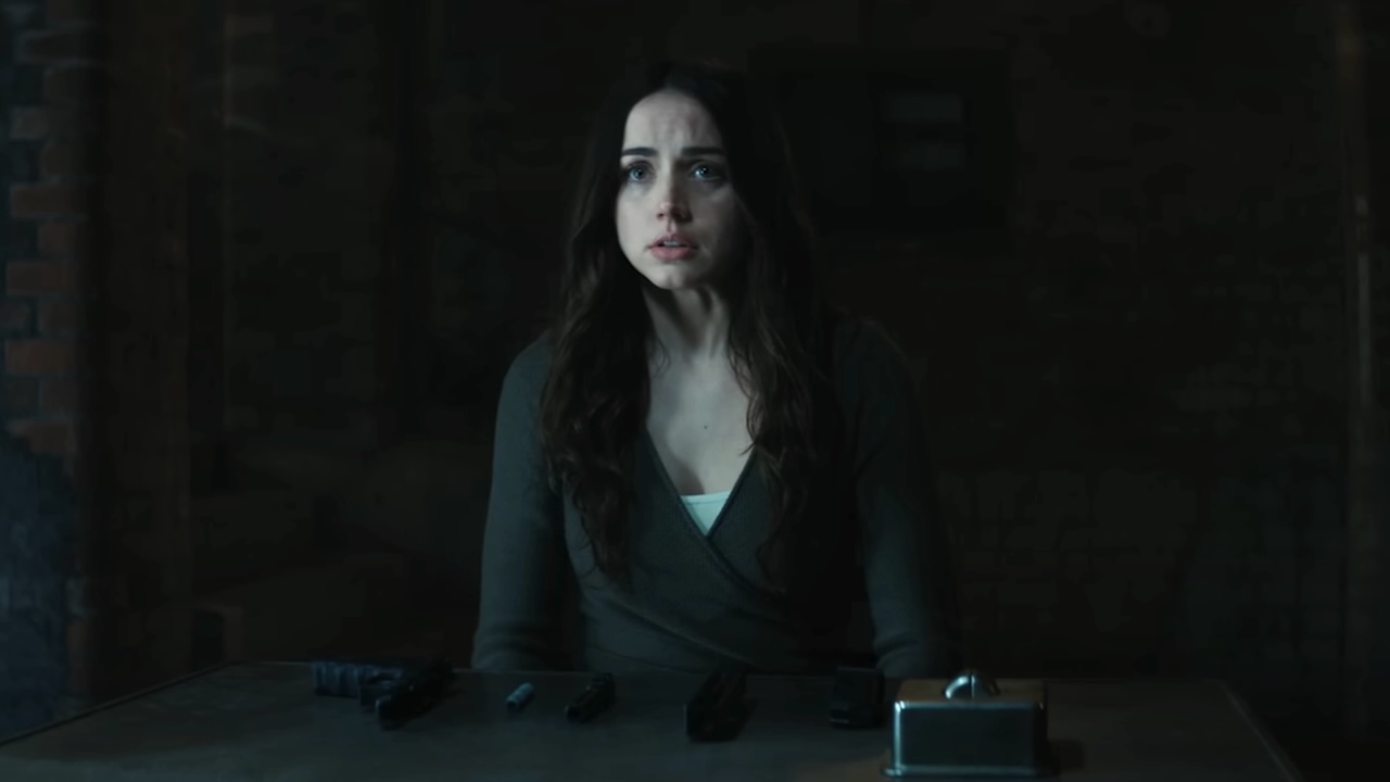 Ana de Armas&#039; Eve sitting at table with a disassembled gun on it in Ballerina