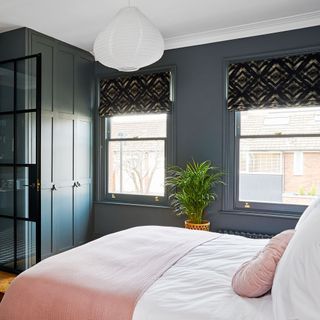 bedroom with two windows and built in storage cupboards painted in a dark green shade