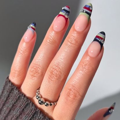 a hand with a sweater manicure wearing a gray knit sleeve and a silver ring