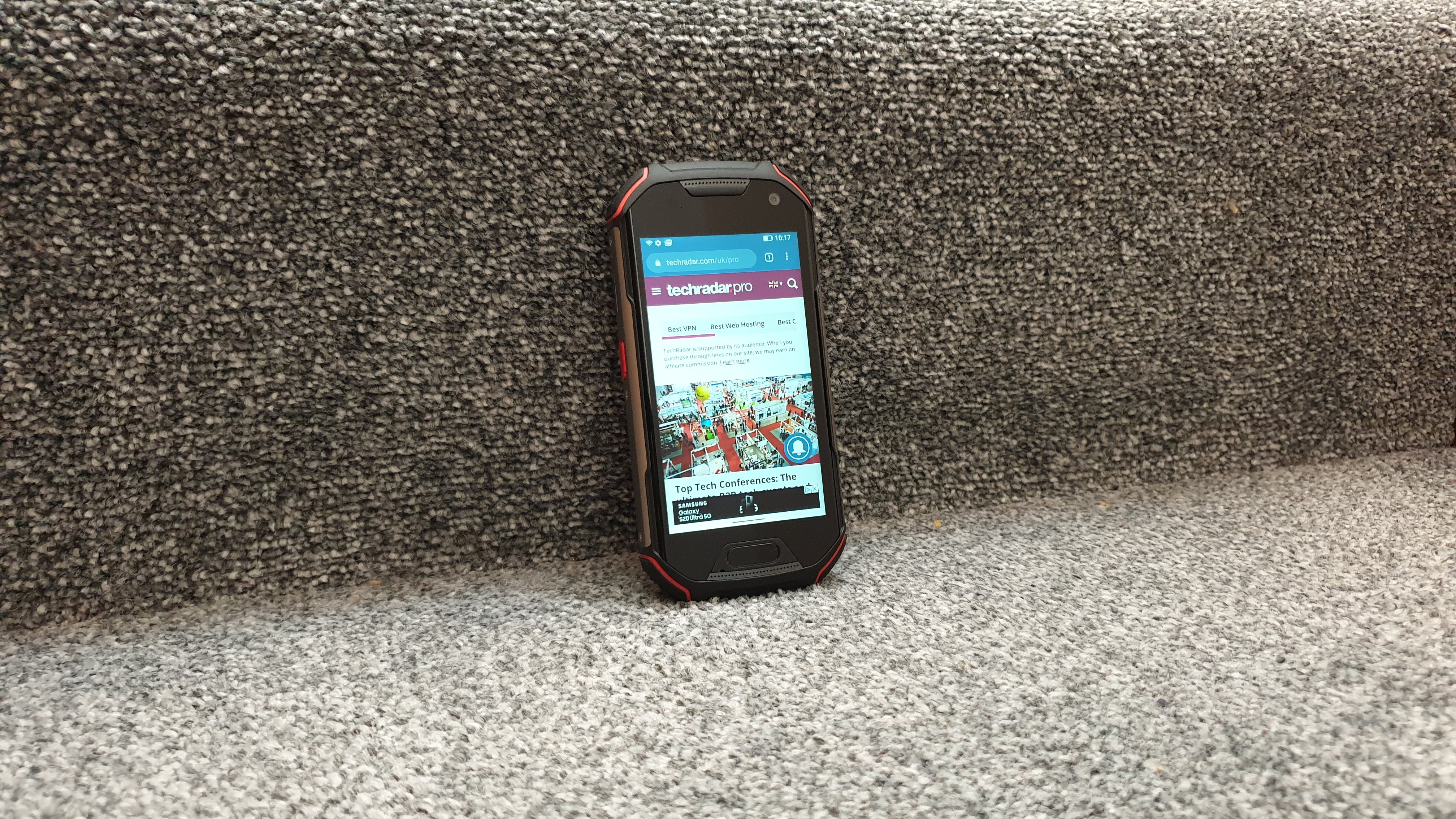 En robust mobiltelefon av typen Unihertz Atom XL står lent mot et trappetrinn.