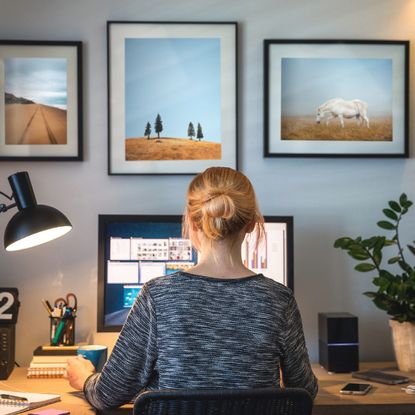 A woman working at a desk with a plant