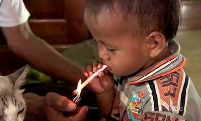 Another Indonesian toddler lights up a cigarette with the help of his grandfather: One third of the country's kids try smoking before the age of 10.