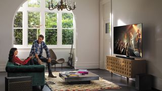 Ein Mann und eine Frau schauen sich einen Samsung QLED-Fernseher in einem Wohnzimmer an