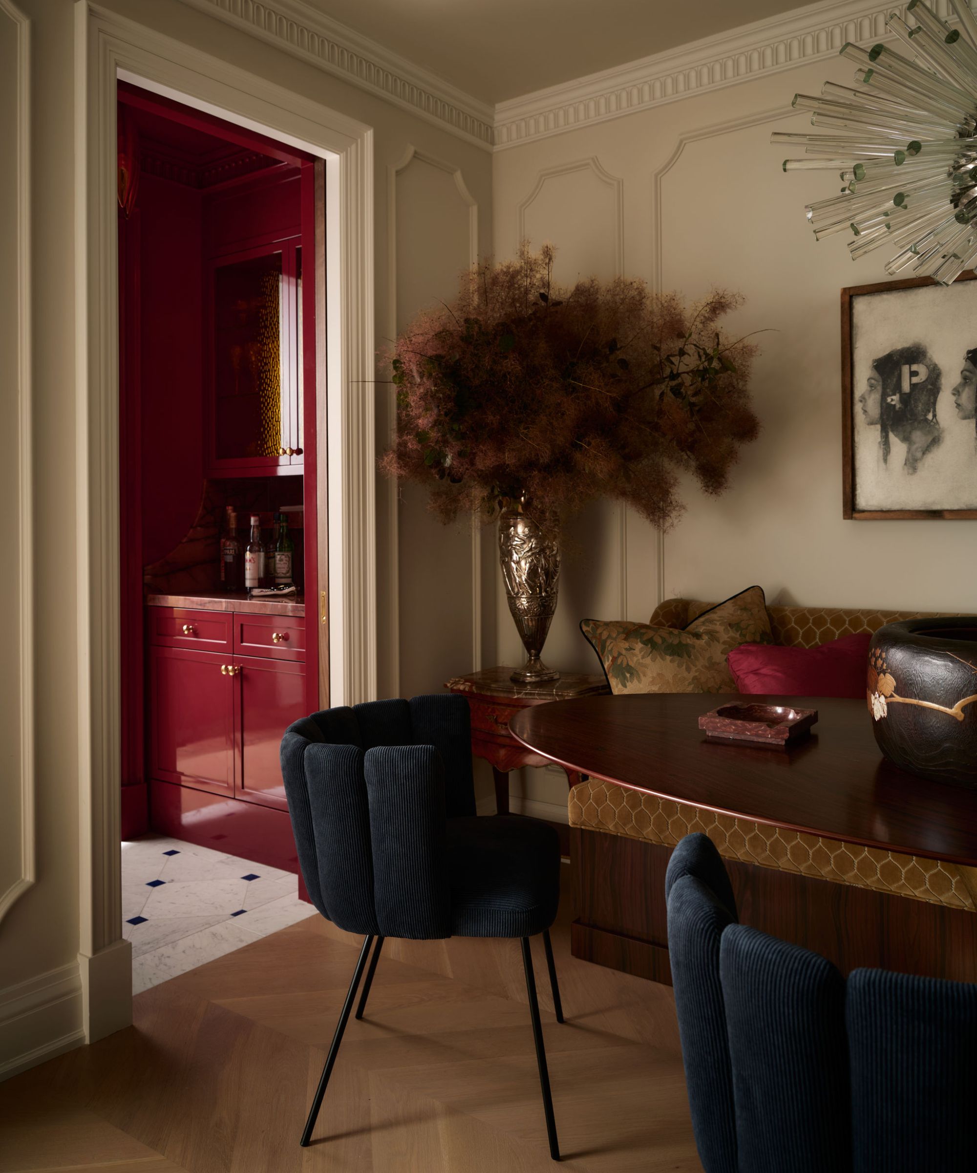 a grand dining room with paneled walls, a banquette seat, blue chairs and a separate bar area through a door