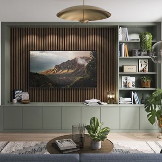 Green built-in furniture across a living room wall with wooden panelling and wall-hung TV