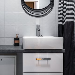 a small black and white bathroom with a white sink and a dark vanity