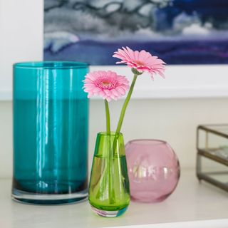 table with flower in vase blue coloured glass and wallpaper on wall
