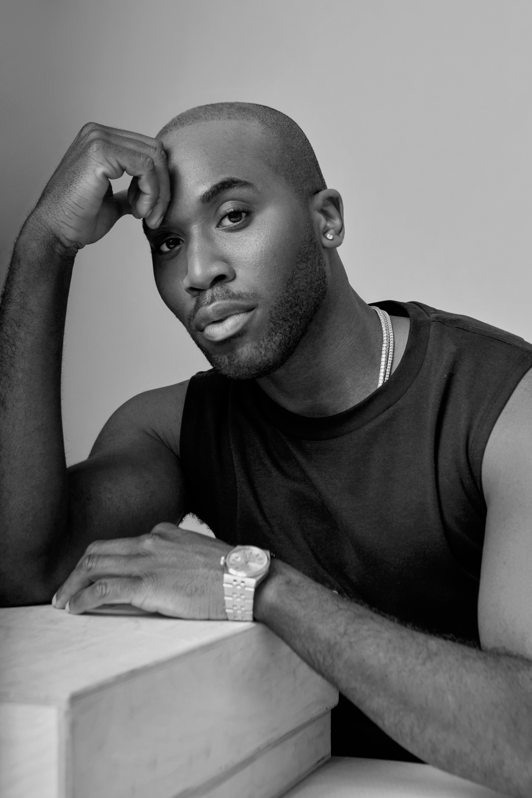 a black man in a black tank top in a black and white photograph with a watch