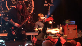 A picture of Napalm Death performing live, with singer Barney Greenway in a wheelchair