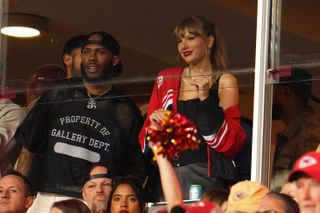 Taylor Swift attends the chiefs x broncos game in 2023 wearing a chiefs windbreaker and a gray pair of pants