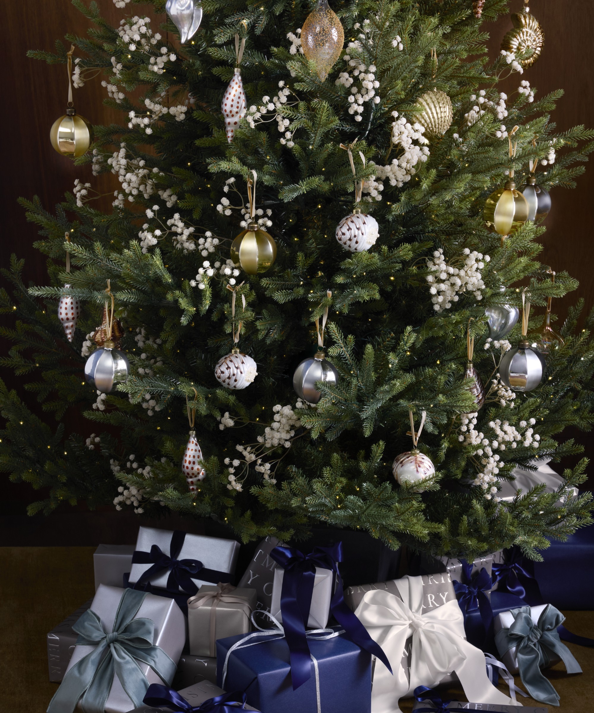 A close-up of a decorated John Lewis Cotswold Christmas tree surrounded by presents