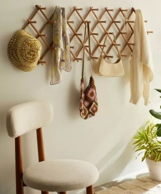 A set of storage hooks on a white wall with a wooden chair below them