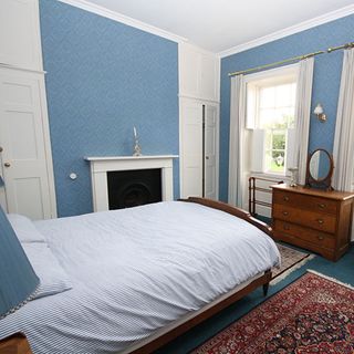 bedroom with blue wall and white door and window and fireplace
