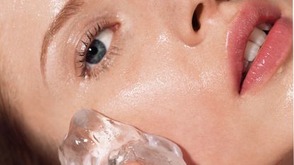 Woman putting ice on her face - stock photo