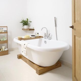 White bathroom with free standing bath and pine shelves