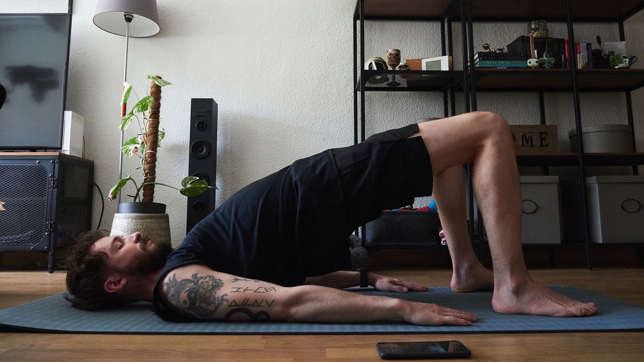 Man doing Pilates bridge pose in apartment