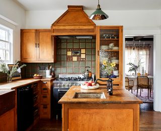kitchen with wooden cabinets, island , green tiled splashback and green pendant light