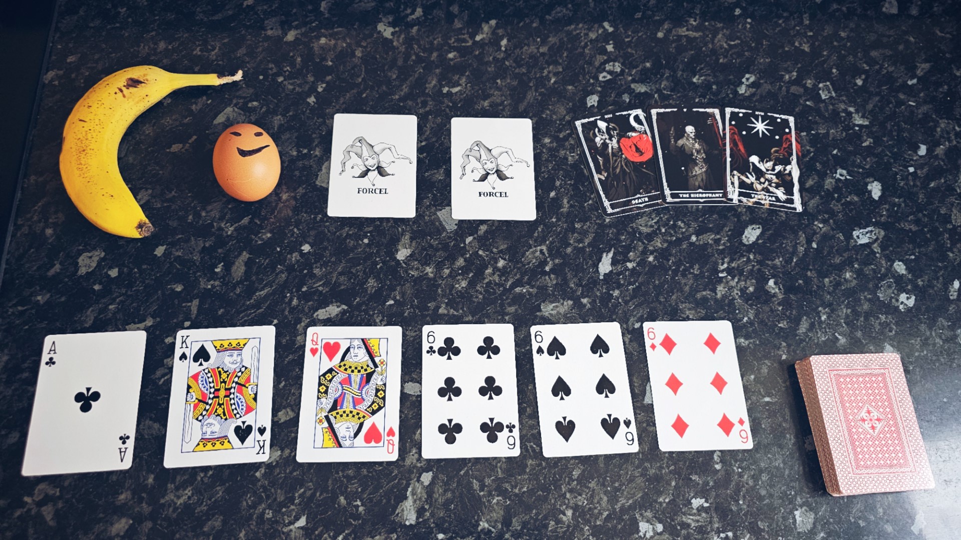 Playing cards, a banana, tarot cards and an egg arranged in the style of Balatro