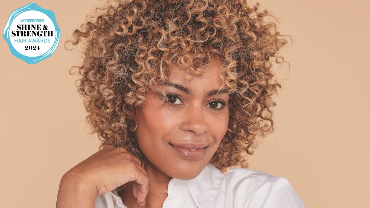 A shot of a woman with a multi-tonal curly hair with a woman&amp;home hair awards logo