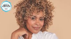 A shot of a woman with a multi-tonal curly hair with a woman&home hair awards logo