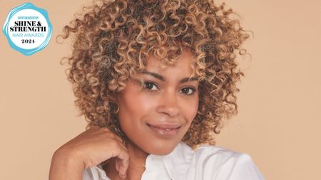 A shot of a woman with a multi-tonal curly hair with a woman&home hair awards logo