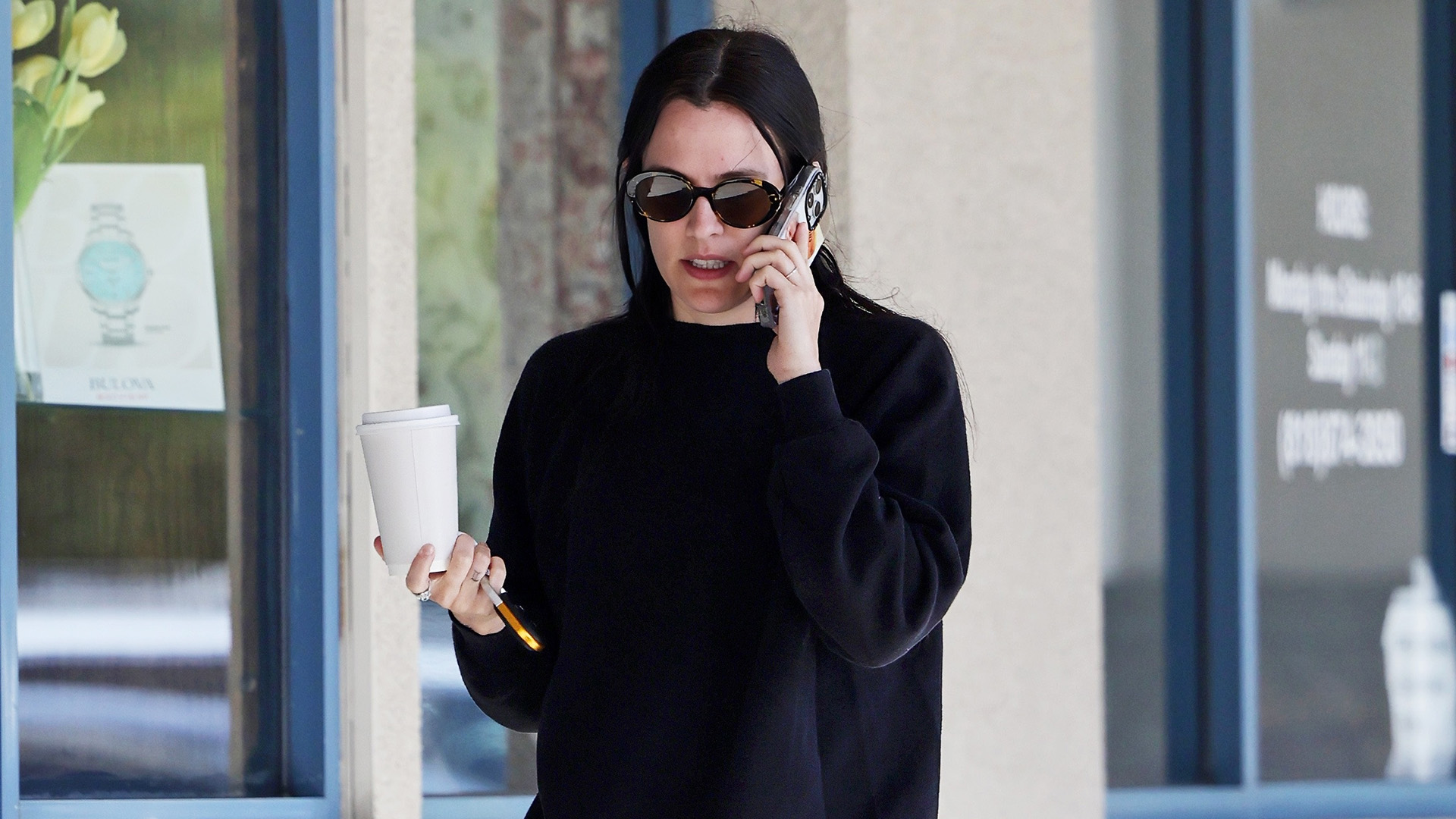 Riley Keough wearing a black top and black leggings with Birkenstock Gizeh sandals. 