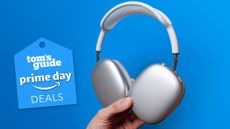AirPods Max in hand next to Prime Day deals tag